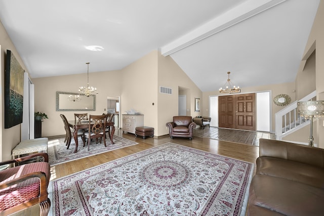 living room with an inviting chandelier, wood finished floors, visible vents, and high vaulted ceiling