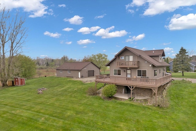 rear view of house featuring a lawn, a balcony, an outbuilding, a detached garage, and a deck