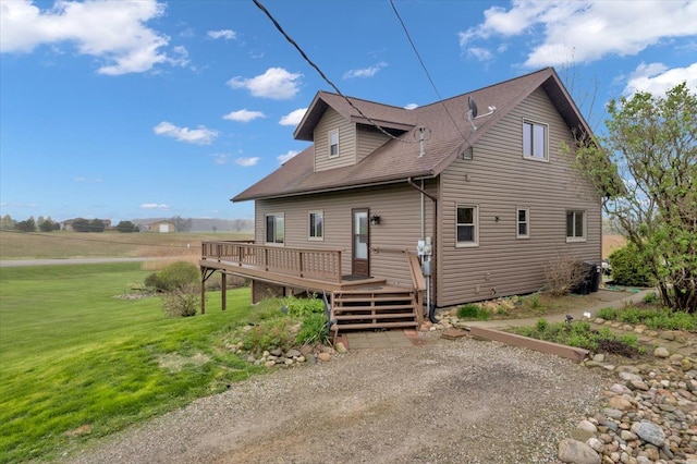 back of house with a yard, a deck, and roof with shingles
