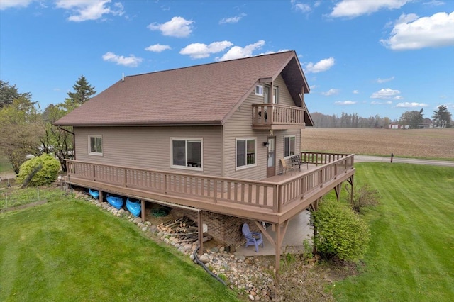 back of house with a lawn, a deck, a shingled roof, and a balcony