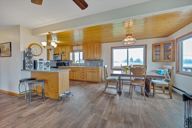 kitchen featuring black electric range oven, dark wood-style flooring, stainless steel microwave, a peninsula, and tasteful backsplash