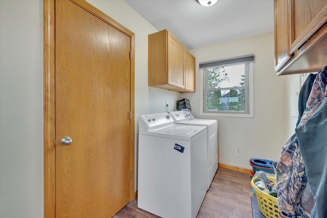 washroom with washing machine and clothes dryer, cabinet space, baseboards, and light wood-style floors