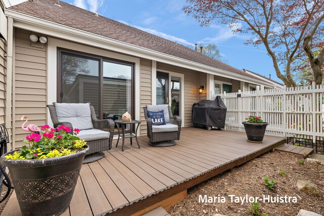 wooden deck featuring fence and a grill
