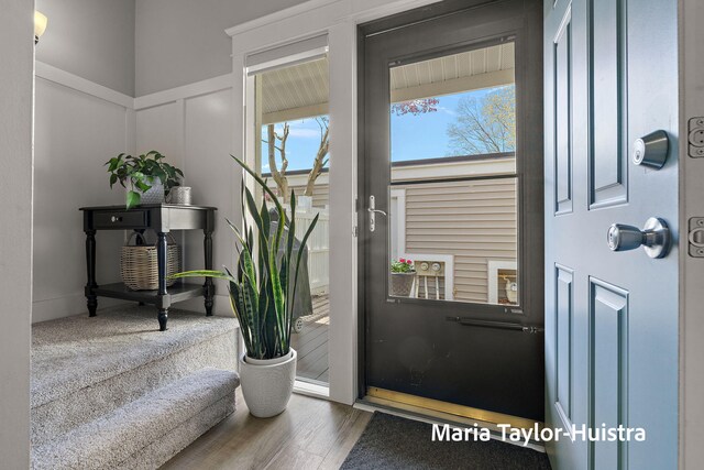 entryway with a wainscoted wall, a decorative wall, and wood finished floors