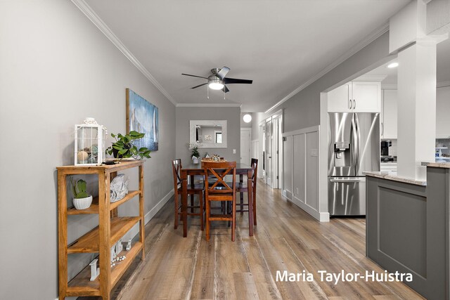 dining room with crown molding, light wood finished floors, ceiling fan, and baseboards