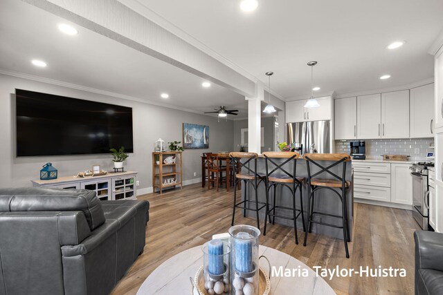 living area featuring baseboards, ornamental molding, light wood finished floors, and recessed lighting