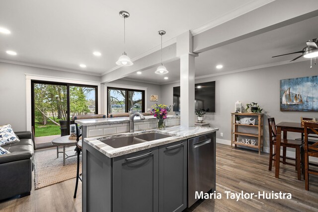 kitchen with a sink, dishwasher, a center island with sink, wood finished floors, and ornamental molding