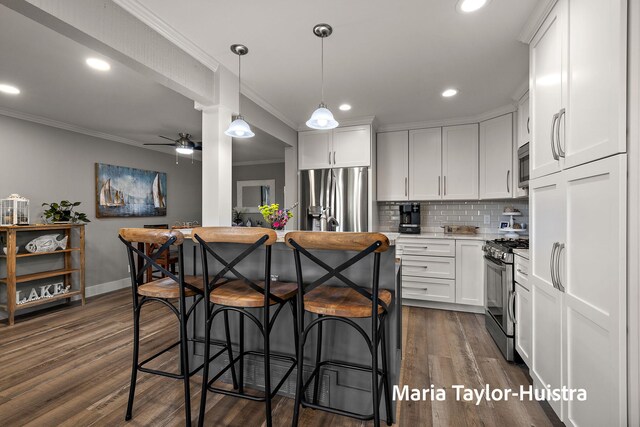 kitchen with white cabinets, stainless steel appliances, a ceiling fan, decorative backsplash, and ornamental molding