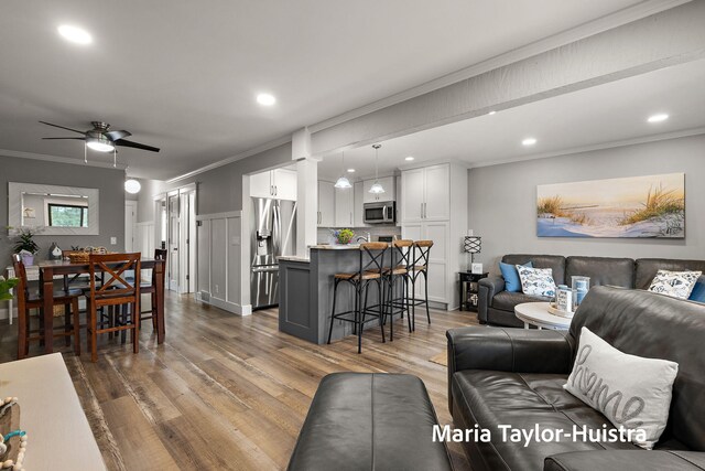 living area with crown molding, recessed lighting, ceiling fan, and dark wood-style floors