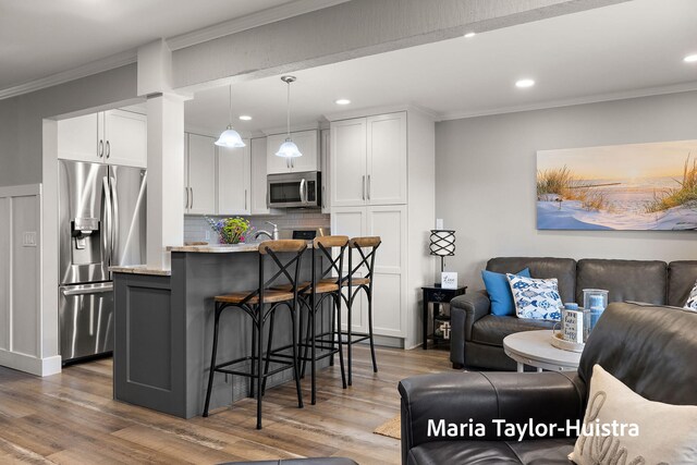 kitchen with a kitchen breakfast bar, appliances with stainless steel finishes, tasteful backsplash, wood finished floors, and open floor plan