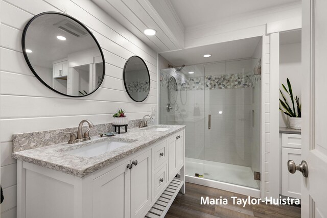 full bathroom featuring a sink, double vanity, a shower stall, and wood finished floors