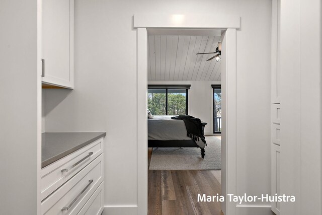 hall featuring baseboards, wooden ceiling, vaulted ceiling with beams, and dark wood-type flooring