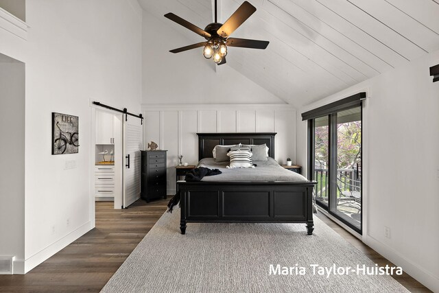bedroom featuring wood finished floors, access to exterior, baseboards, high vaulted ceiling, and a barn door