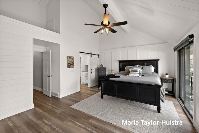 bedroom featuring a barn door, beam ceiling, high vaulted ceiling, wood finished floors, and visible vents