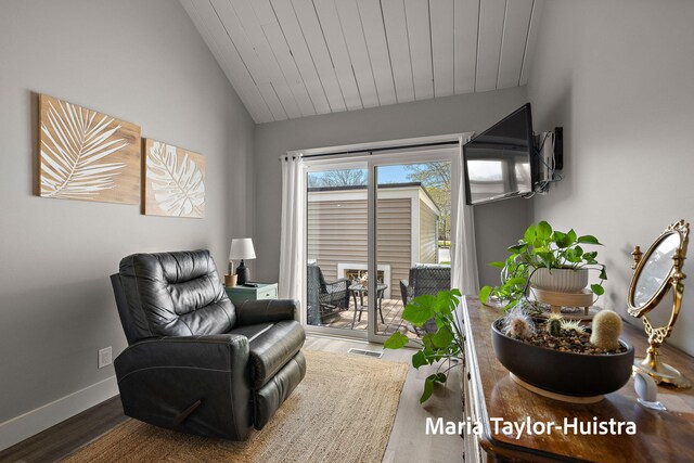 living area with wood finished floors, baseboards, and lofted ceiling