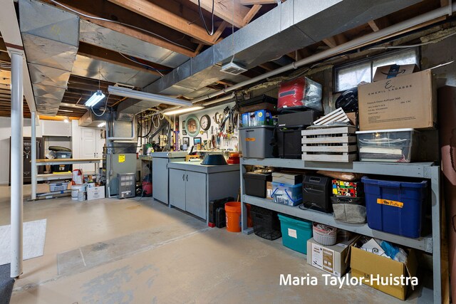 unfinished basement with a workshop area, heating unit, and visible vents