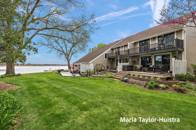 back of house with a balcony, a deck with water view, a patio, an outdoor hangout area, and a lawn