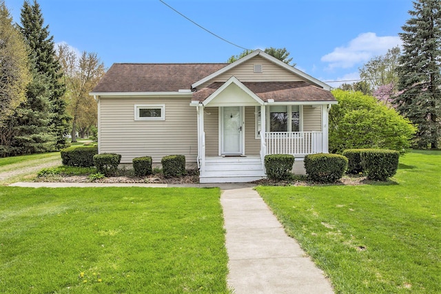 bungalow with roof with shingles, covered porch, and a front lawn