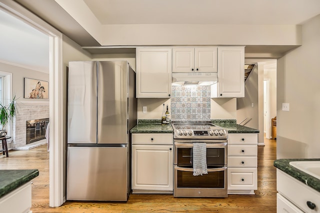 2204 Rivenoak Ct, Ann Arbor, MI 48103 - kitchen with a brick fireplace, light wood-type flooring, under cabinet range hood, white cabinets, and appliances with stainless steel finishes