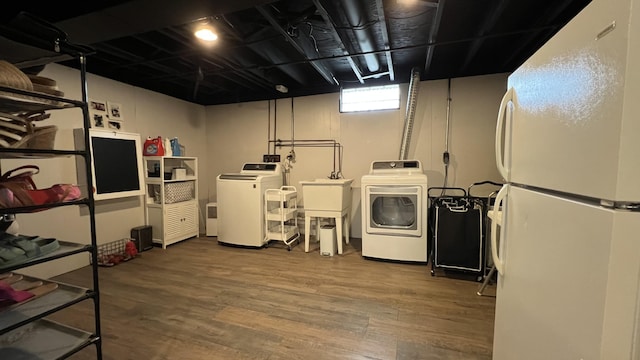 washroom featuring washer and dryer, laundry area, a sink, and wood finished floors