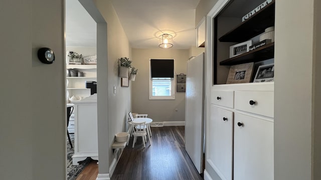 corridor with baseboards, dark wood finished floors, and visible vents
