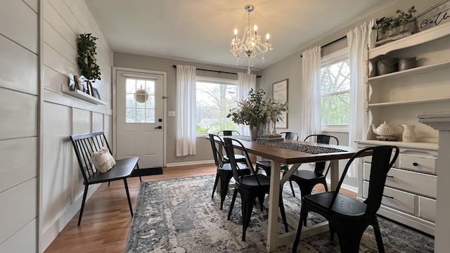 dining area with baseboards, wood finished floors, and a notable chandelier