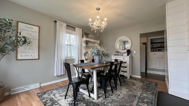 dining room with visible vents, baseboards, wood finished floors, and a chandelier