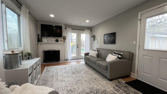 living room featuring plenty of natural light, a brick fireplace, recessed lighting, and wood finished floors