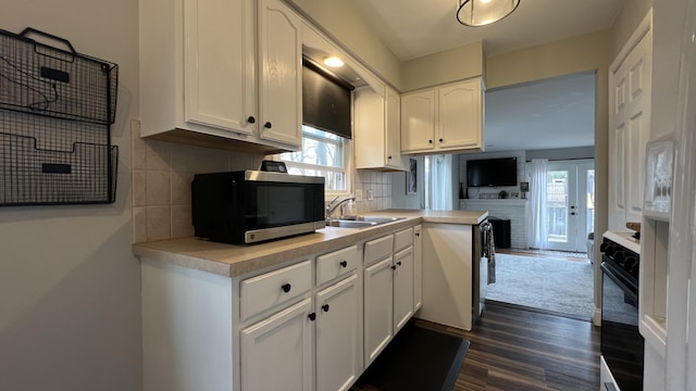 kitchen with decorative backsplash, a sink, light countertops, white cabinets, and stainless steel microwave