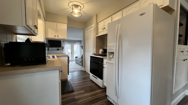 kitchen featuring white cabinets, black microwave, white refrigerator with ice dispenser, dark wood finished floors, and range with gas stovetop