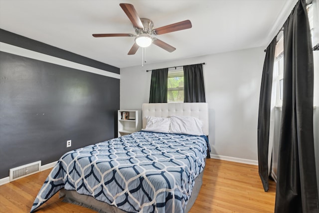 bedroom featuring visible vents, a ceiling fan, baseboards, and wood finished floors