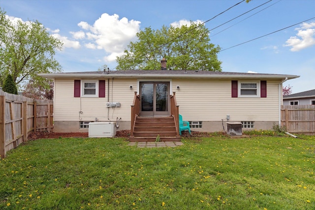 rear view of house featuring a lawn, a fenced backyard, and entry steps
