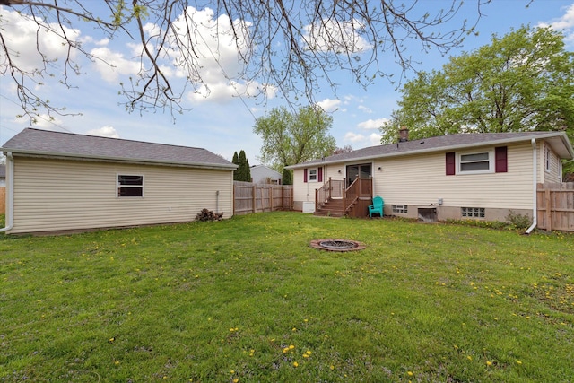 back of house with fence, a lawn, and a fire pit