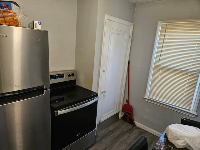 kitchen featuring baseboards, dark wood-style flooring, and stainless steel appliances
