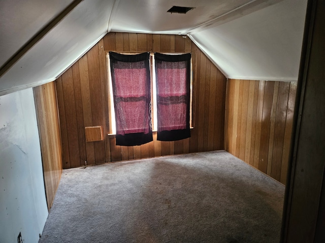 bonus room featuring carpet flooring, wood walls, and vaulted ceiling