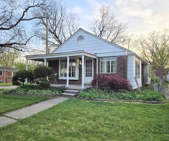 view of front facade featuring brick siding, a front lawn, and a porch