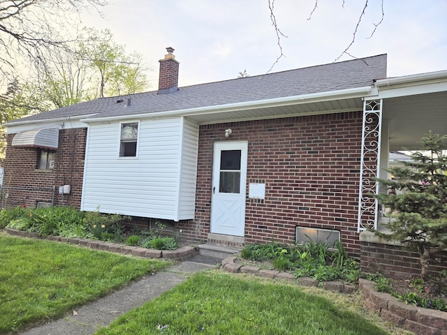 back of house featuring entry steps, a chimney, and brick siding