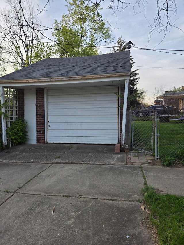 garage featuring fence and concrete driveway