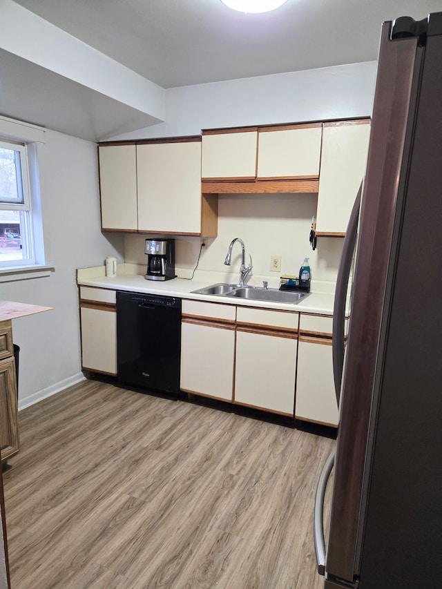 kitchen with freestanding refrigerator, light wood-style floors, light countertops, a sink, and dishwasher