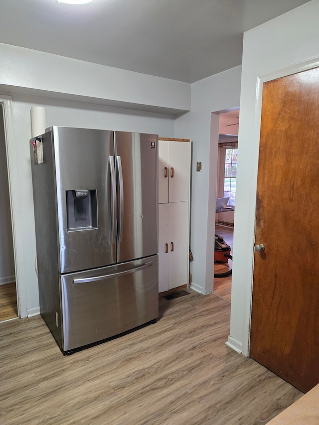 kitchen with baseboards, stainless steel fridge, and light wood-style floors