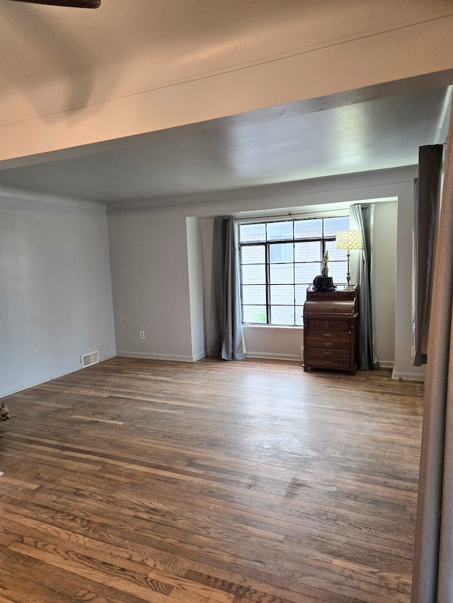 empty room featuring baseboards, dark wood finished floors, and visible vents