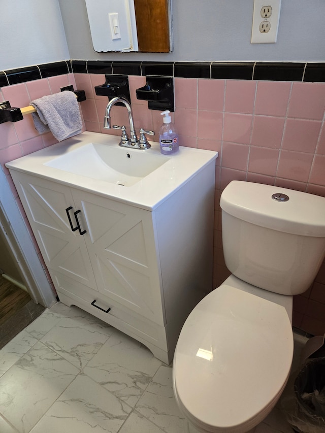 bathroom with vanity, marble finish floor, wainscoting, toilet, and tile walls