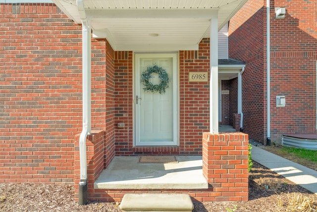 doorway to property with brick siding and a porch