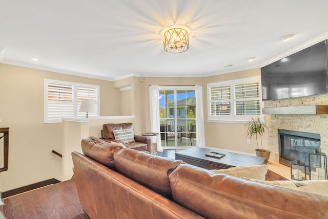living room with a stone fireplace, ornamental molding, wood finished floors, and a wealth of natural light