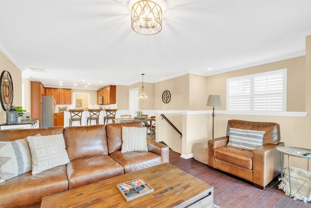 living room featuring an inviting chandelier, ornamental molding, wood finished floors, and visible vents
