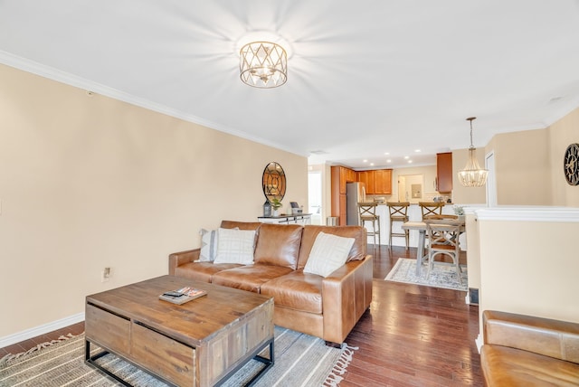 living area featuring baseboards, ornamental molding, dark wood-style flooring, and a notable chandelier