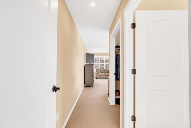 hall featuring light colored carpet and baseboards