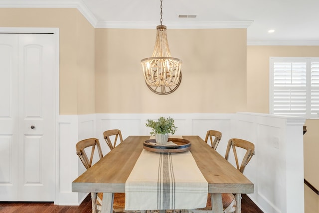 dining area featuring a notable chandelier, ornamental molding, wood finished floors, and visible vents
