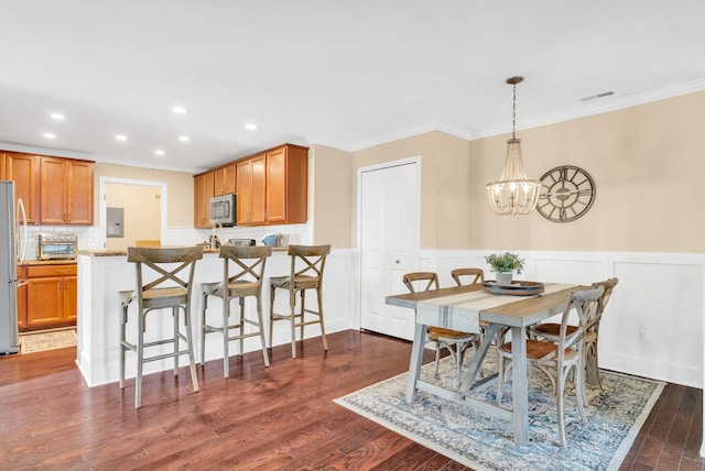 dining space featuring crown molding, a chandelier, visible vents, and wainscoting