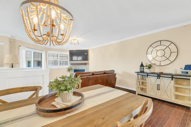 dining area featuring crown molding, dark wood finished floors, a chandelier, and a fireplace